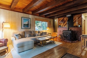 A cozy living room with a fireplace, a sofa, and a coffee table. - Charming West Shore Chalet, Great Location, Close to the Lake, Hiking and Biking (Tahoma)