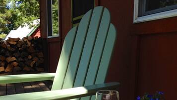 Ein grüner Adirondack-Stuhl mit einem Glas Weißwein und einem Blumentopf auf einem Tisch.