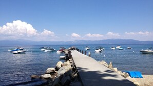 Un muelle con barcos amarrados, cielo despejado y montañas al fondo.
