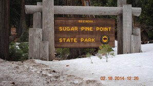 Un letrero de madera en el Parque Estatal Sugar Pine Point, con el nombre del parque y un logotipo de oso.