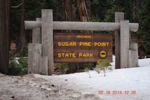 Un senyal de fusta al parc estatal Sugar Pine Point amb el nom del parc i un logotip d'ós.