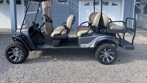 Un golf cart parcheggiato di fronte a una casa con garage e recinzione bianca.