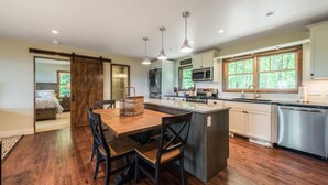 A modern kitchen with a central island, wooden flooring, and pendant lighting. -  Peaceful and luxurious living with spectacular views  (Spruce Pine)