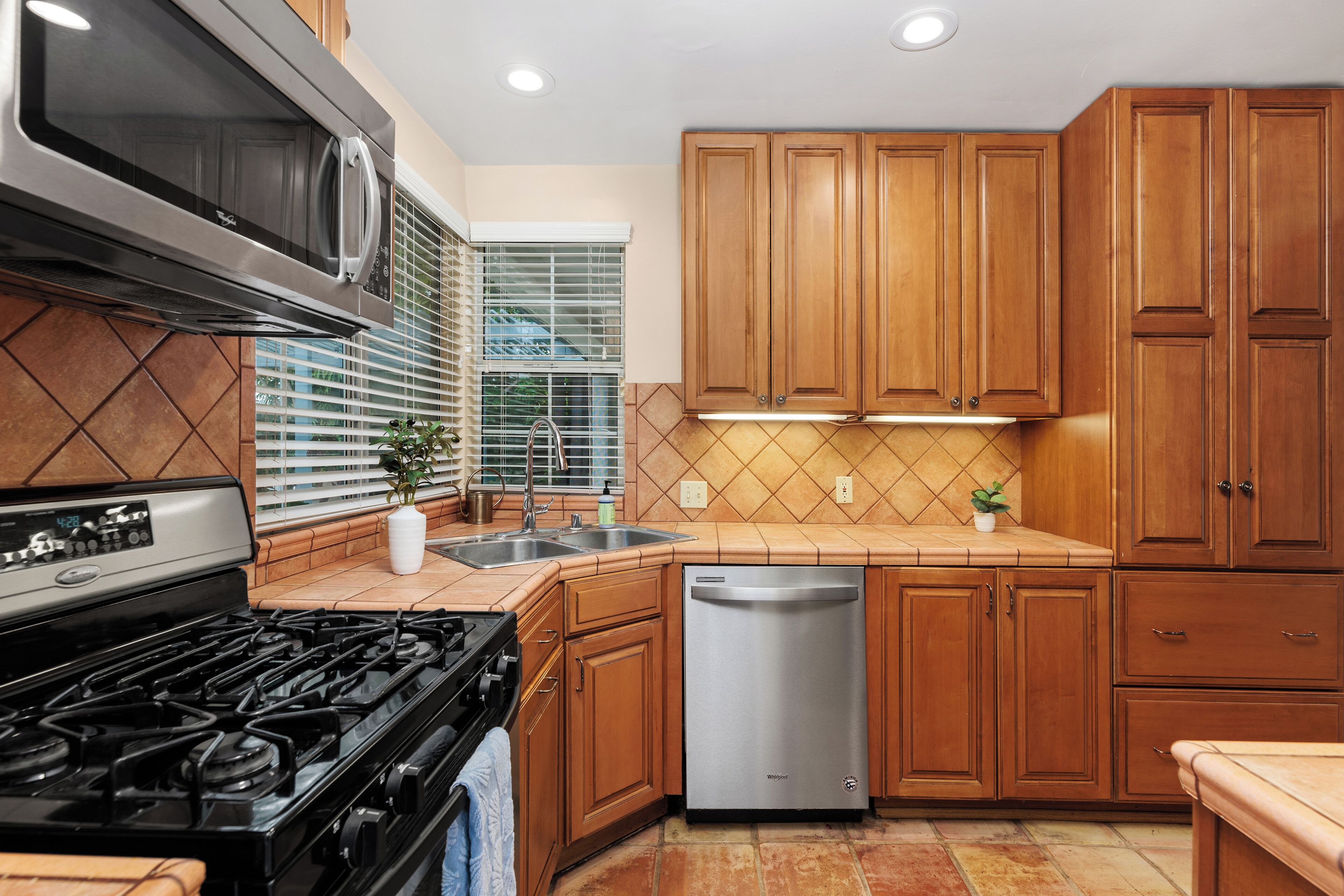 A kitchen with wooden cabinets, a stainless steel dishwasher, and a black stove.