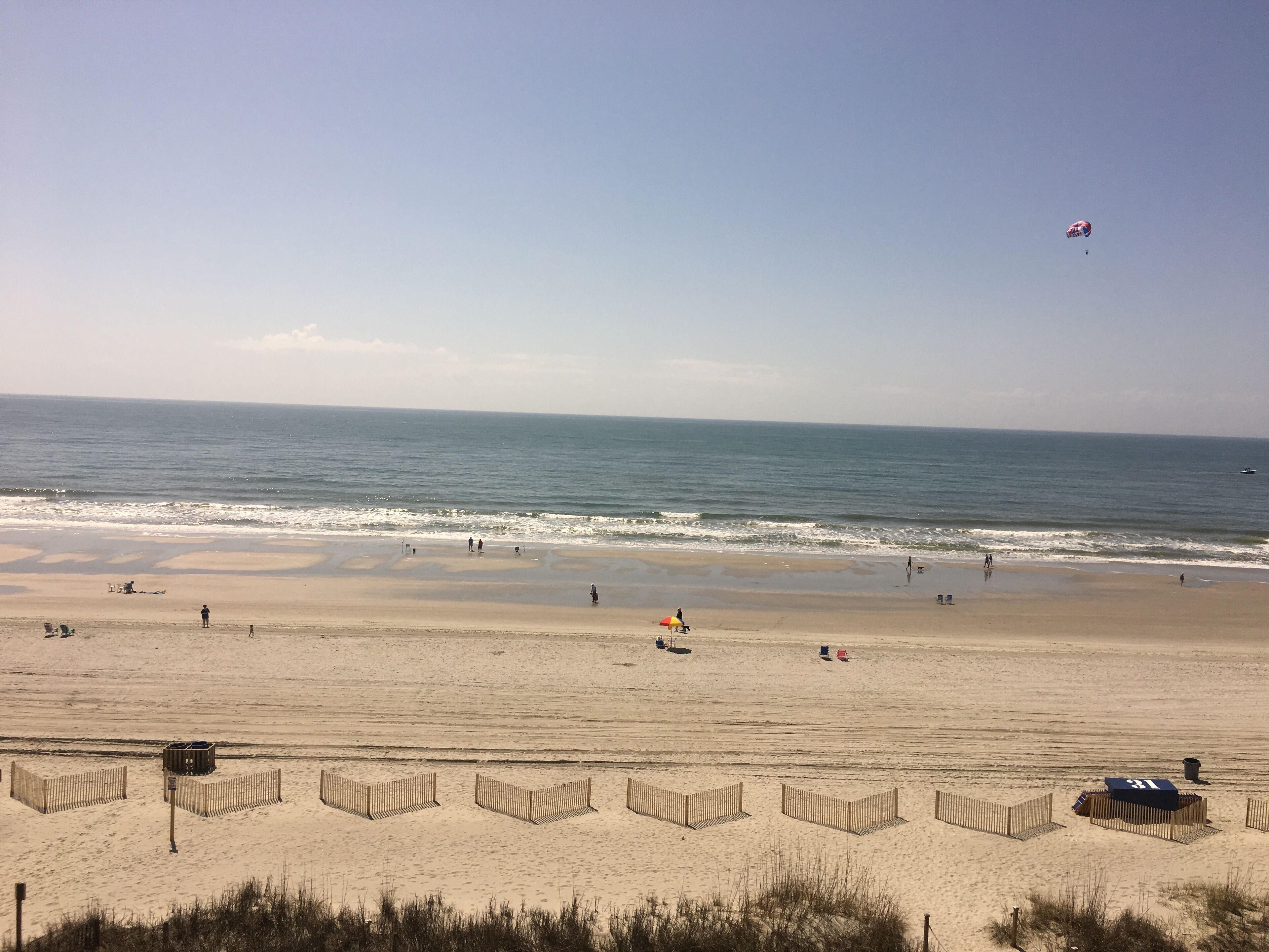 A beach with a wooden fence, a lifeguard tower, and a clear view of the ocean.