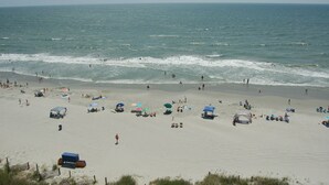 Una playa con gente, sombrillas y sillas de playa.