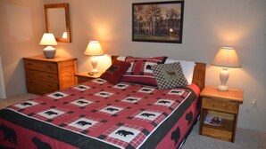 Een slaapkamer met een bed, twee nachtkastjes, een spiegel en een schilderij aan de muur.