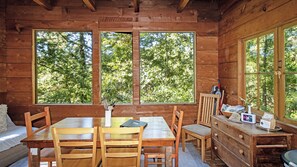 Eine Holzhütte mit Esstisch, Stühlen, einer Bank und einem Schminktisch mit Spiegel und kleiner Tisch.
