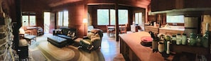 A cozy cabin interior with a fireplace, a sofa, a dining table, and a kitchen area with a sink and jars.