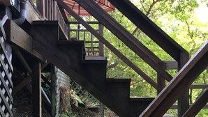 A wooden staircase with a metal handrail leading to a covered outdoor area. - The Treehouse - a Romantic Russian River Retreat (Guerneville)