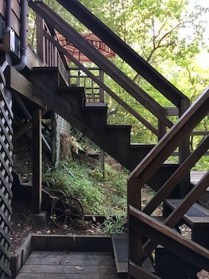 A wooden staircase with a metal handrail leading to a covered outdoor area.
