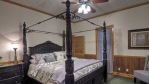 A four-poster bed with a ceiling fan, a nightstand with a lamp, a dresser, and a chair. - 2 Blocks From Marketplatz & The Heart Of Main Street Shopping And Dining! (Fredericksburg)