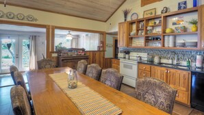 A spacious kitchen with wooden cabinets, a dining table with patterned chairs, and a ceiling fan. - 2 Blocks From Marketplatz & The Heart Of Main Street Shopping And Dining! (Fredericksburg)