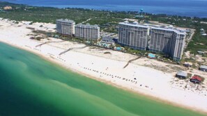 A coastal hotel with multiple high-rise buildings, a beach, and a clear view of the ocean.