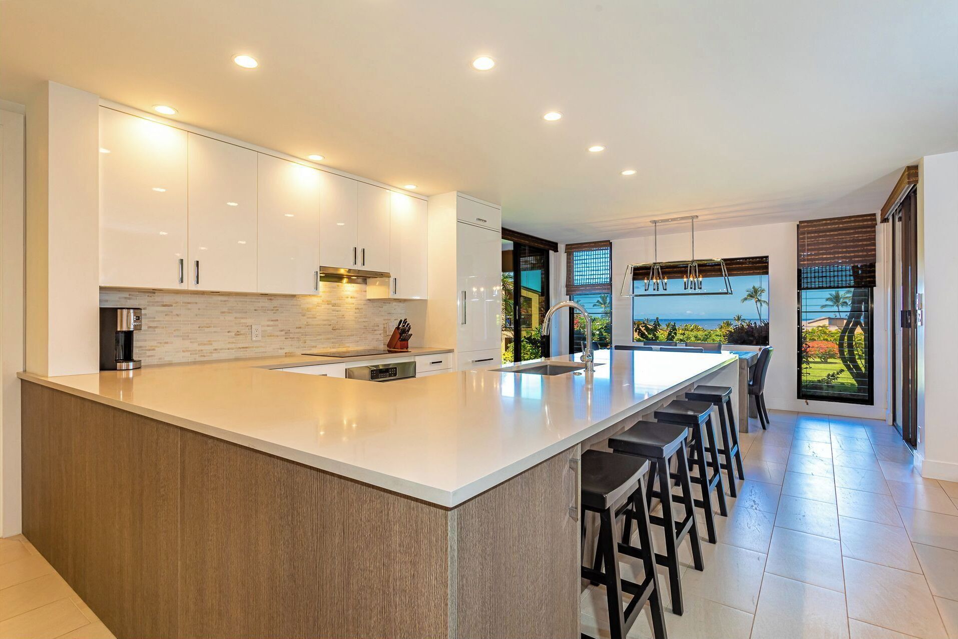 Una cocina moderna con una isla grande, electrodomésticos integrados y vistas al océano.