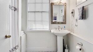 A bathroom with a window, a sink, a mirror, a towel rack, and a toilet paper holder. - Colonial Park Retreat! Historic District Prime Location! (Savannah)