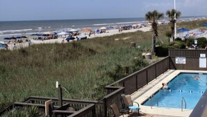 A beach view with a pool area, including a wooden deck and lounge chairs. - Oceanfront Pet Friendly 3 BR Condo (North Myrtle Beach)