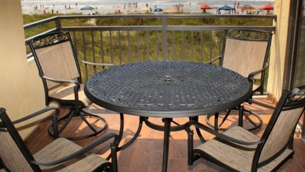 A round metal table with four chairs on a balcony overlooking a beach. - Oceanfront Pet Friendly 3 BR Condo (North Myrtle Beach)