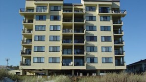 A multi-story hotel with balconies, located near a sandy beach. - Oceanfront Pet Friendly 3 BR Condo (North Myrtle Beach)