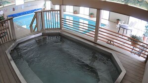 Un jacuzzi sur une terrasse, avec une piscine en arrière-plan.
