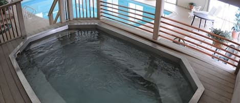 Ein Whirlpool auf einer Terrasse, im Hintergrund ein Schwimmbad.