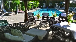 An outdoor pool area with lounge chairs and tables, surrounded by greenery. - Walk to Restaurants, Wineries and More (Saint Helena)