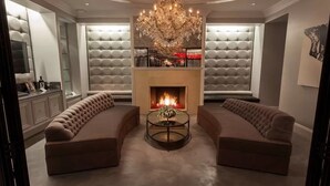 A luxurious living room with a fireplace, two sofas, a chandelier, and a glass coffee table. - Walk to Restaurants, Wineries and More (Saint Helena)