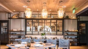 A restaurant with wooden ceiling, glass-fronted shelves, and tables set for dining. - Walk to Restaurants, Wineries and More (Saint Helena)