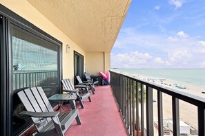 Een balkon met zitplaatsen buiten, uitzicht op het strand en een heldere lucht.