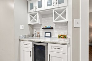 A kitchen with white cabinetry, a dishwasher, and a marble countertop.