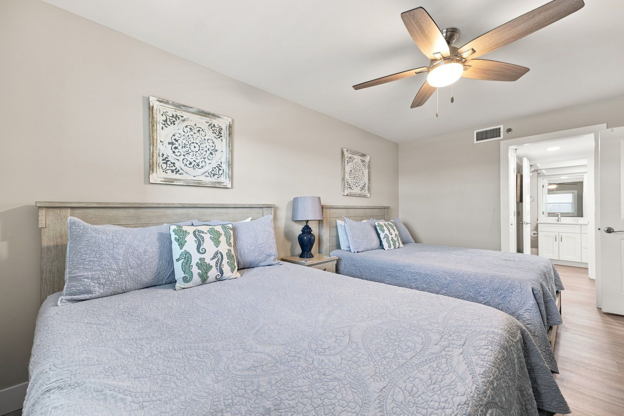 A hotel room with two beds, a ceiling fan, and a bathroom visible through an open door.