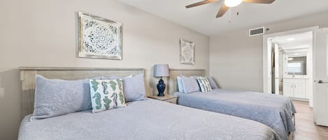 A hotel room with two beds, a ceiling fan, and a bathroom visible through an open door.