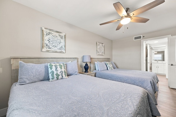 A hotel room with two beds, a ceiling fan, and a bathroom visible through an open door.