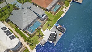 Una propiedad residencial con una piscina grande, un porche cubierto y un muelle que se extiende sobre el agua.