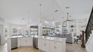 Una cocina moderna con armarios blancos, una isla central e iluminación colgante.