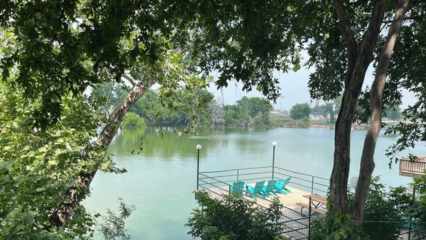 Vista de un lago con un área cercada que incluye sillas verdes y un farol.