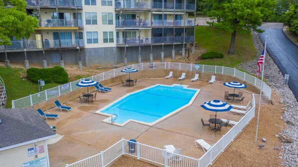 A pool area with lounge chairs and umbrellas, surrounded by a white fence.