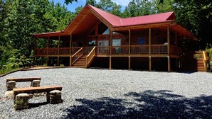 A two-story log cabin with a red roof, a covered porch, and a gravel driveway. - Brooke's Place Deep Creek Area in Bryson City- Luxury Cabin (Bryson City)