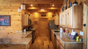 A wooden cabin-style kitchen with granite countertops, wooden cabinets, and a central island. - Brooke's Place Deep Creek Area in Bryson City- Luxury Cabin (Bryson City)