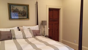 A neatly made bed with striped bedding, a framed picture on the wall, and a wooden door. - Location, Beauty & Free Parking In Downtown Capitol Hill! (Washington)