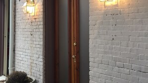 A white brick building with a wooden door and two wall-mounted lantern-style lights. - Location, Beauty & Free Parking In Downtown Capitol Hill! (Washington)