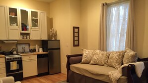 A compact living space with a kitchenette, a sofa with patterned cushions, and a dining area. - Location, Beauty & Free Parking In Downtown Capitol Hill! (Washington)