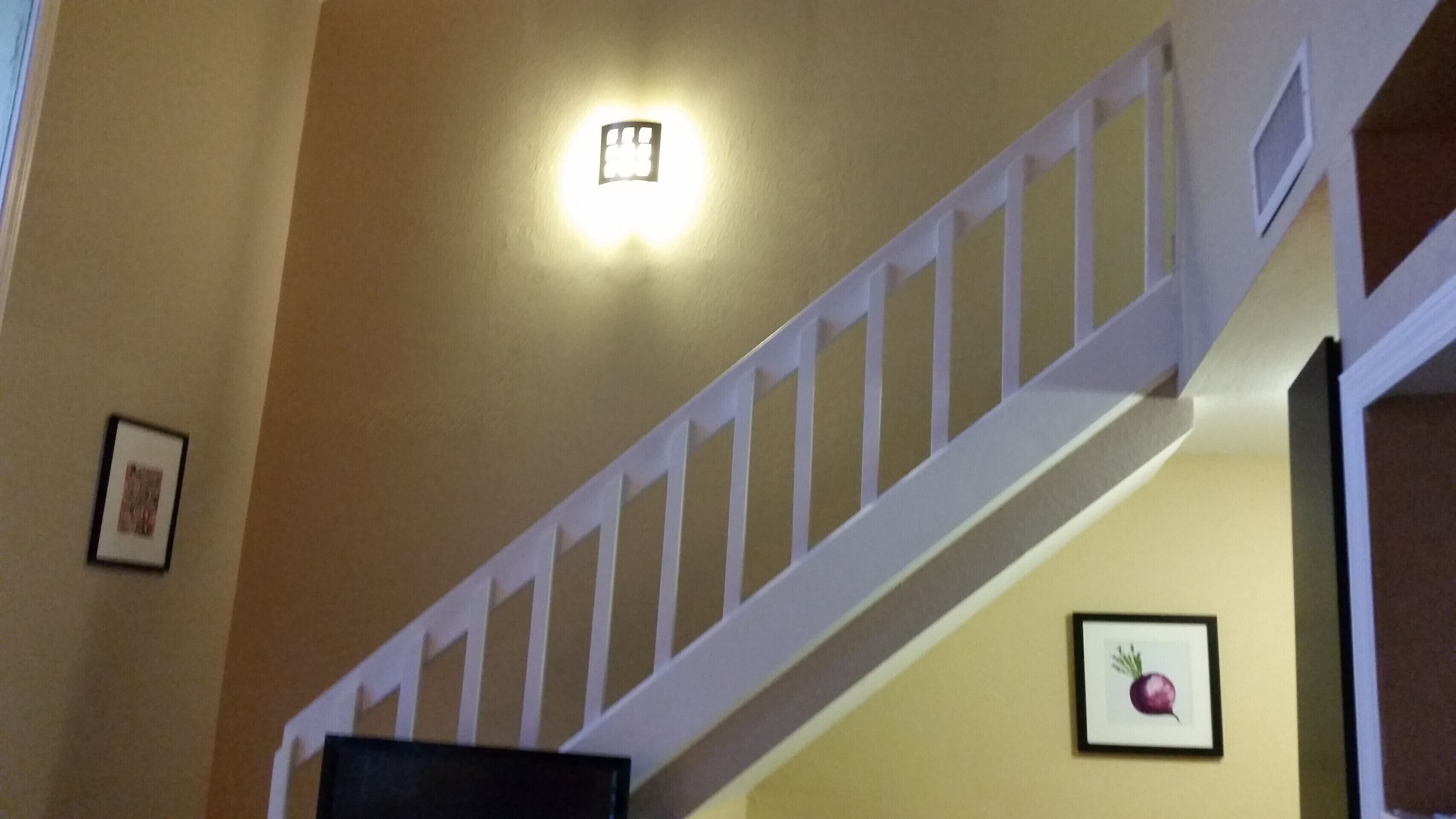 Eine Treppe mit weißen Geländern und einer Wandleuchte.