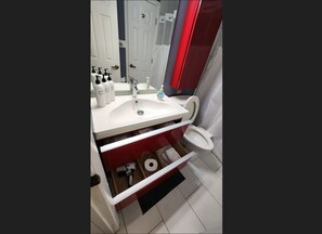 Un baño moderno con un lavabo blanco, un mueble de color rojo y un inodoro.