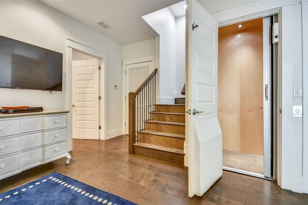 Eine Treppe führt zu einer zweiten Etage, eine weiße Tür und ein Flachbildfernseher an der Wand.