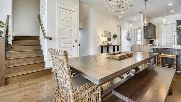 A spacious dining area with a long wooden table, wicker chairs, and a modern chandelier. - Amazing pet-friendly family getaway w/elevator, game room, 7 bikes, & EV charger (Seacrest Beach)