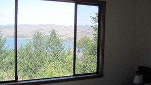 A bedroom with a large window offering a view of a lake and hills. - Frank's Place: Classic Inverness  Home with Bay Views, Hot Tub (Inverness)