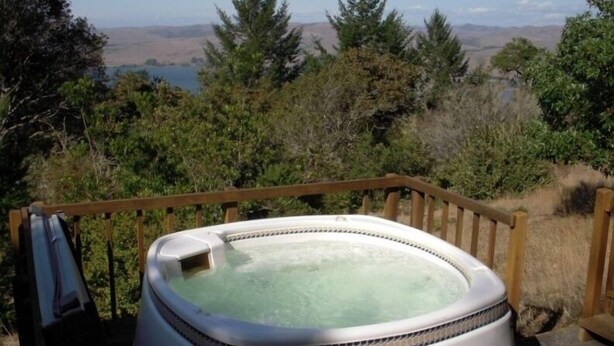 A hot tub on a wooden deck with a view of trees and hills. - Frank's Place: Classic Inverness  Home with Bay Views, Hot Tub (Inverness)