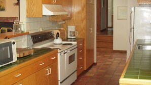 A kitchen with wooden cabinets, a stove, a microwave, and a sink. - Frank's Place: Classic Inverness  Home with Bay Views, Hot Tub (Inverness)