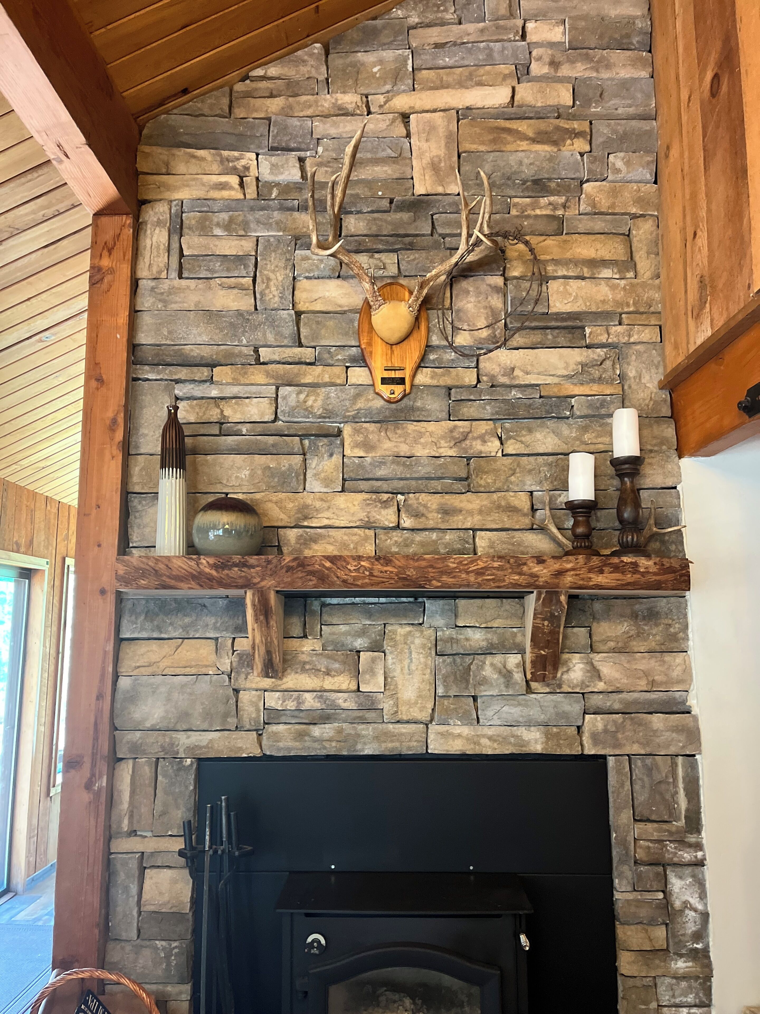 A stone fireplace with a mounted deer head and candles.